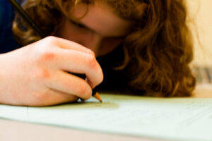 gros plan sur une main de petite fille qui écrit avec un crayon sur une page blanche