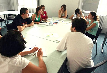 groupe d'étudiants et étudiantes autour d'une table blanche ovale, photo prise au Collège européen de Cluny