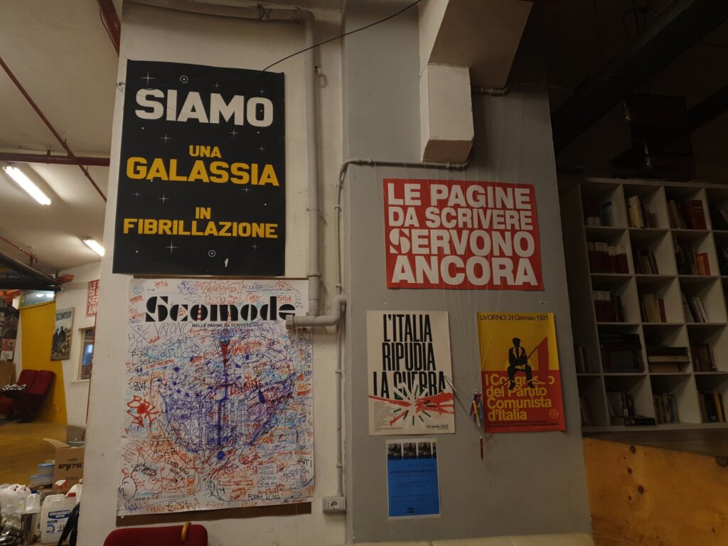 Photo de couvertures d'un journal accrochées au mur et une affiche le pagine da scrivere sevono ancora