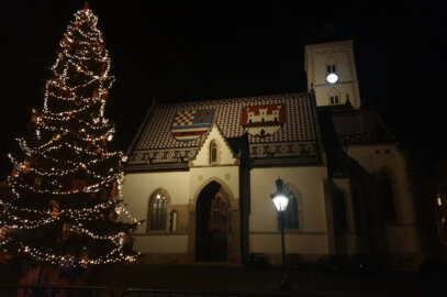 Photo de nuit d'une maison avec le toit décoré de céramique représentant des blasons, à côté d'un grand sapin illuminé