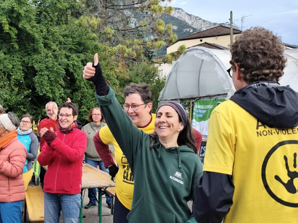 Personne avec un tshirt Alternatiba, au milieu d'un groupe, souriante et levant un pouce.